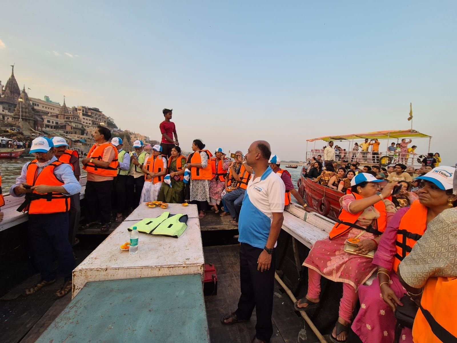 Tour group enjoying a traditional boat ride on the Ganga River in Varanasi, exploring famous ghats like Dashashwamedh and Assi during sunrise
