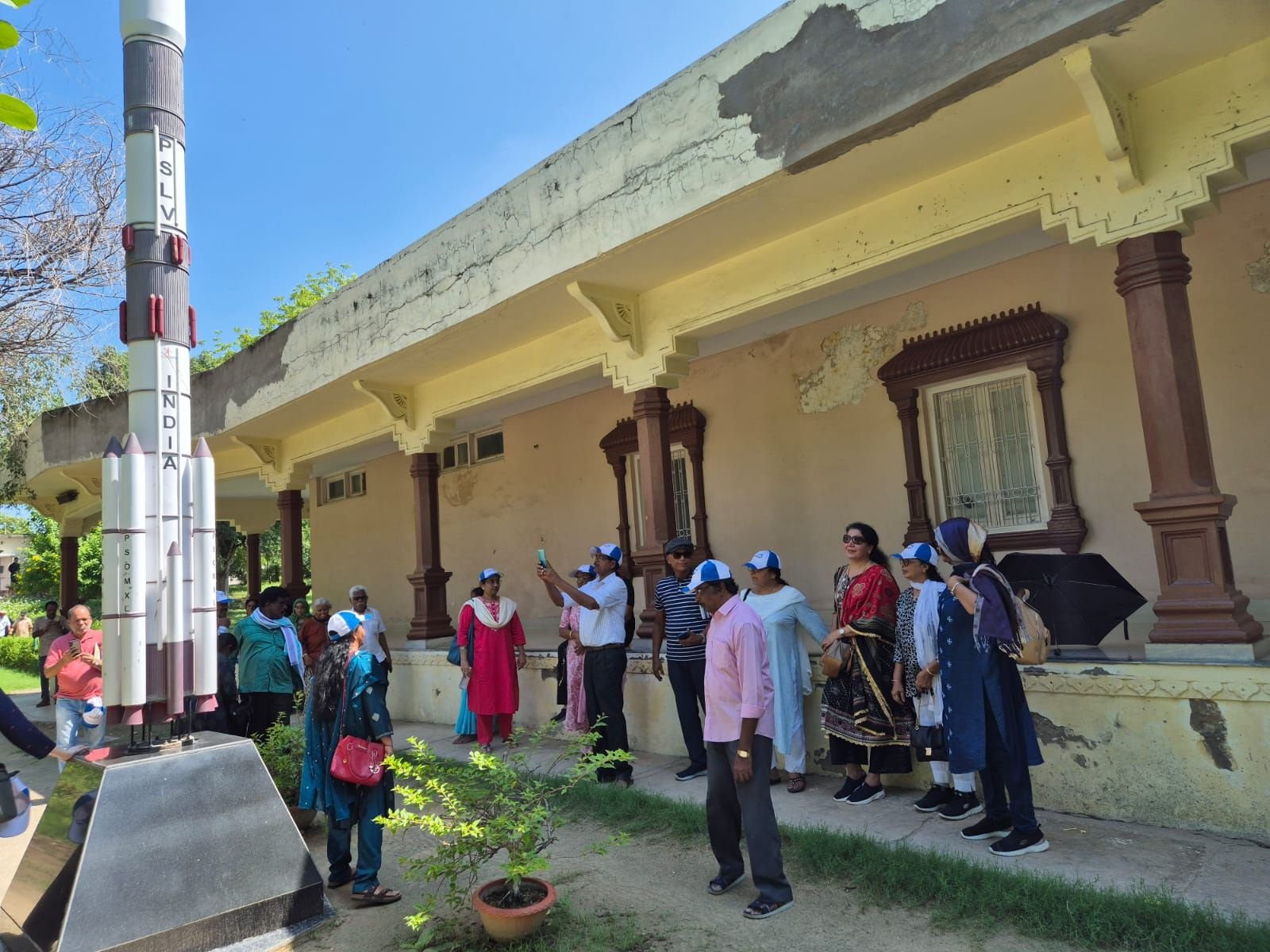 Group of tourists standing beside the PSLV rocket model at Jawahar Planetarium in Prayagraj, Uttar Pradesh